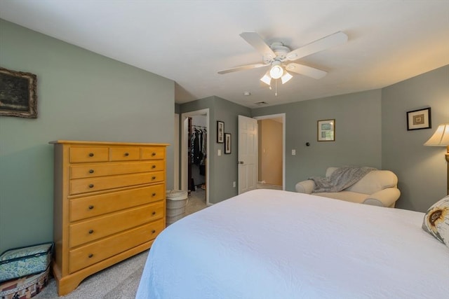 bedroom with light colored carpet, a ceiling fan, a spacious closet, and a closet