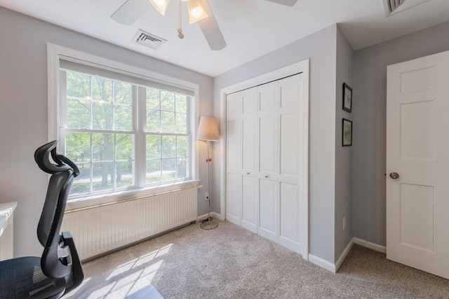 exercise area with radiator heating unit, a ceiling fan, carpet, and baseboards