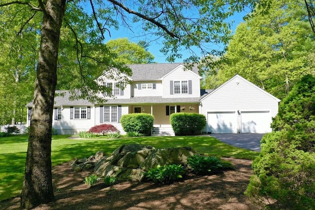 traditional-style home with a garage, a front yard, asphalt driveway, and a shingled roof