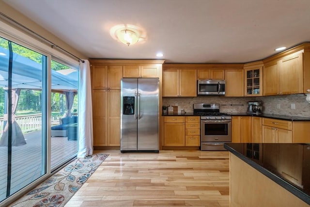 kitchen with appliances with stainless steel finishes, light wood-style flooring, backsplash, glass insert cabinets, and recessed lighting
