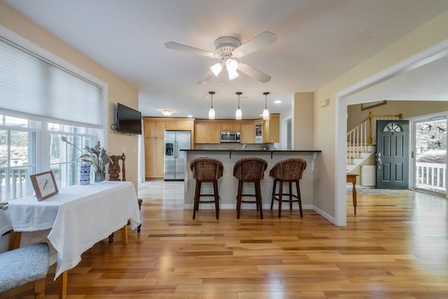 dining room with a ceiling fan, light wood-type flooring, stairway, and baseboards