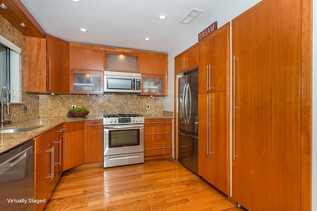 148 Greenbrook Dr Unit 69-6, Stoughton, MA 02072 - kitchen with appliances with stainless steel finishes, a sink, brown cabinetry, tasteful backsplash, and light stone counters