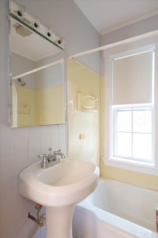 bathroom with tile walls, bathing tub / shower combination, and crown molding