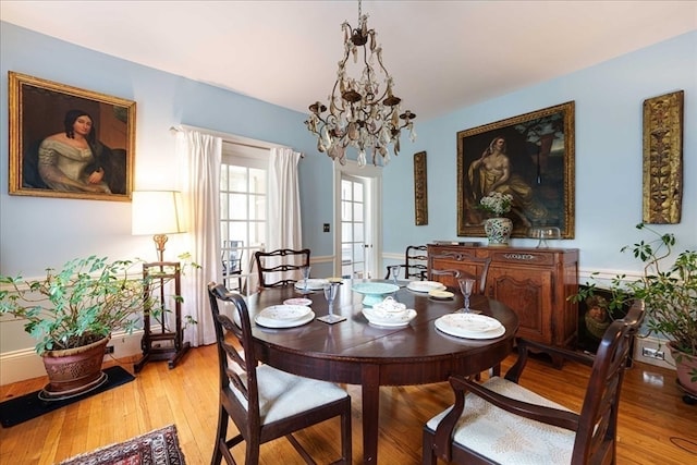 dining space with light wood-type flooring and a chandelier