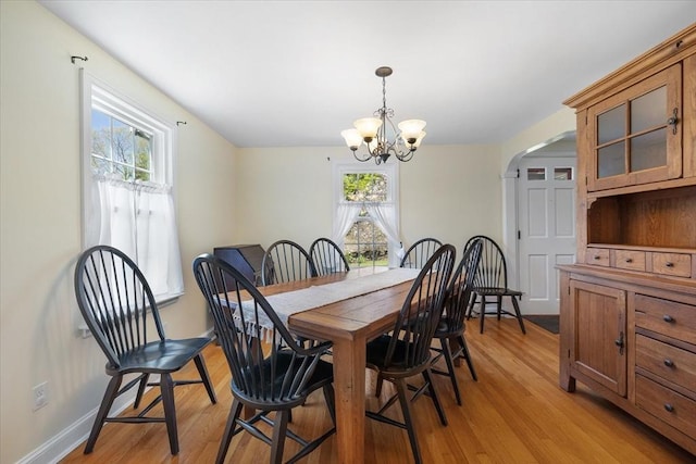 dining space featuring baseboards, a notable chandelier, and light wood finished floors