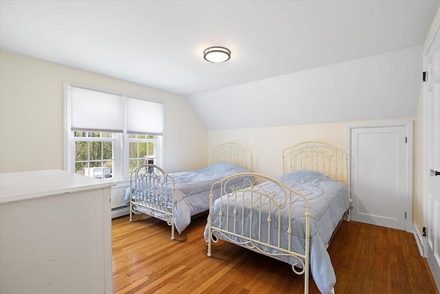 bedroom with baseboard heating, vaulted ceiling, and light wood-style flooring