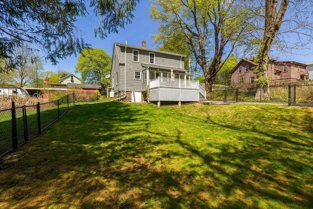 back of property with a lawn, a fenced backyard, a chimney, and a deck