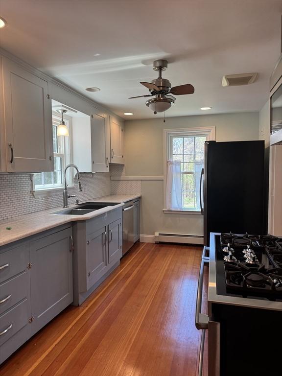 kitchen featuring a sink, gray cabinets, backsplash, and stainless steel appliances