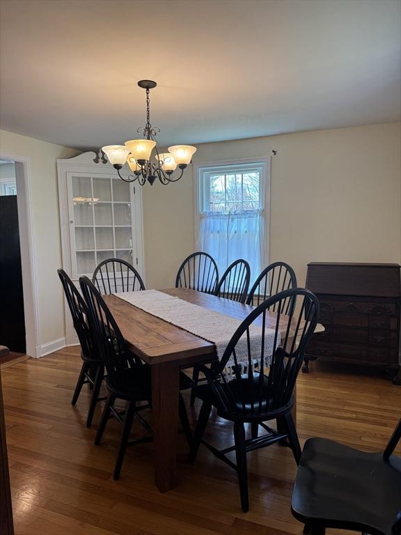 dining space with baseboards, dark wood-type flooring, and a chandelier