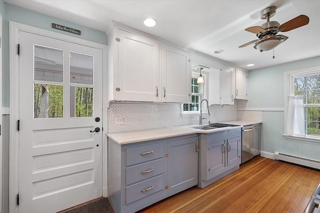 kitchen with a sink, light wood finished floors, dishwasher, gray cabinetry, and a baseboard heating unit