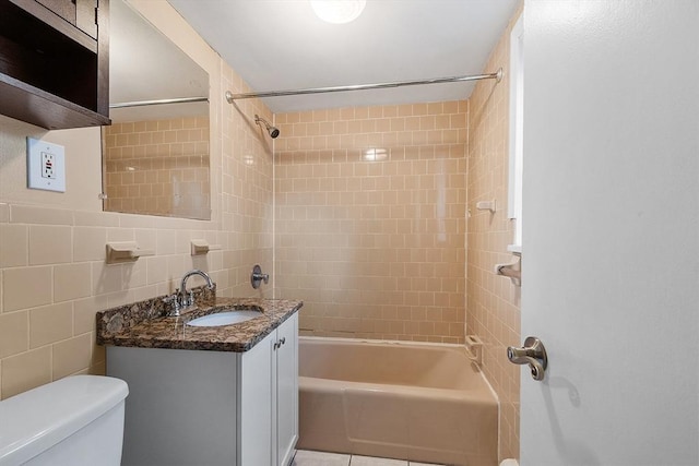 full bathroom with tiled shower / bath, vanity, toilet, and tile walls