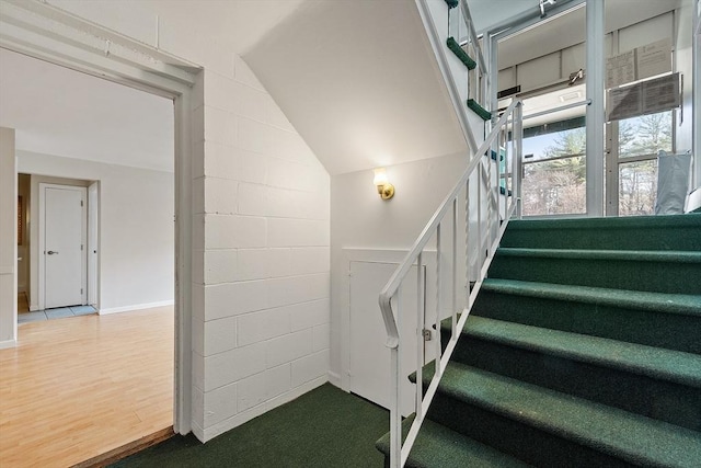 stairway with hardwood / wood-style floors and vaulted ceiling