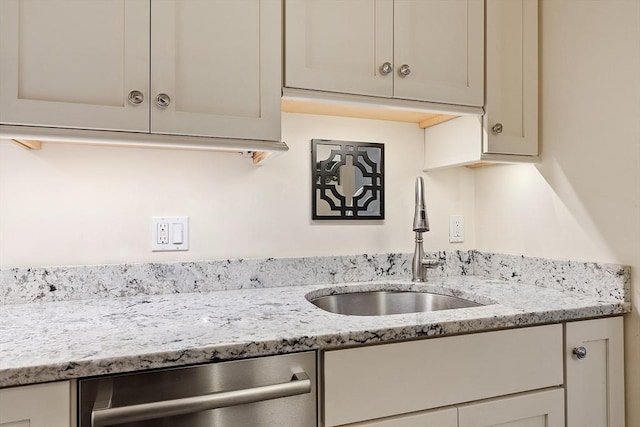 kitchen with dishwasher, light stone counters, and sink