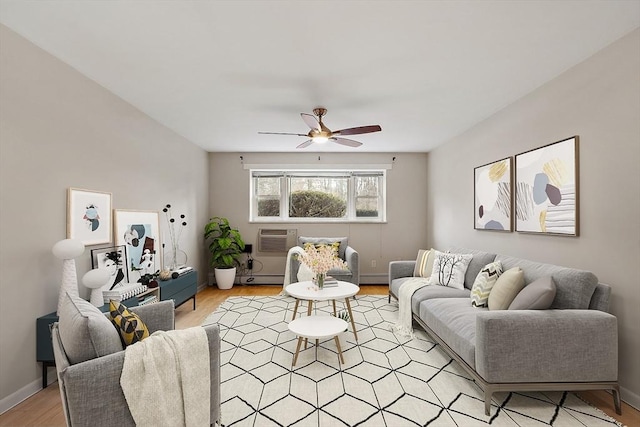 living room featuring ceiling fan, light hardwood / wood-style floors, baseboard heating, and a wall unit AC