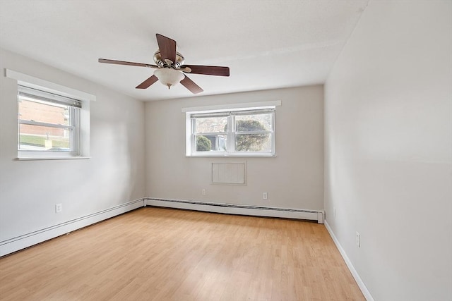 spare room with light wood-type flooring, ceiling fan, and a baseboard heating unit