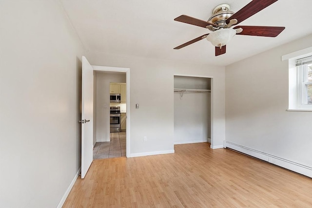 unfurnished bedroom featuring ceiling fan, a closet, light hardwood / wood-style flooring, and a baseboard heating unit