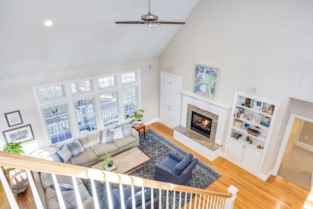 living room with a high end fireplace, ceiling fan, high vaulted ceiling, and hardwood / wood-style flooring