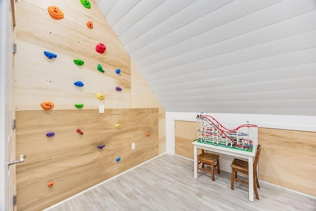 playroom featuring hardwood / wood-style floors, vaulted ceiling, and wooden walls