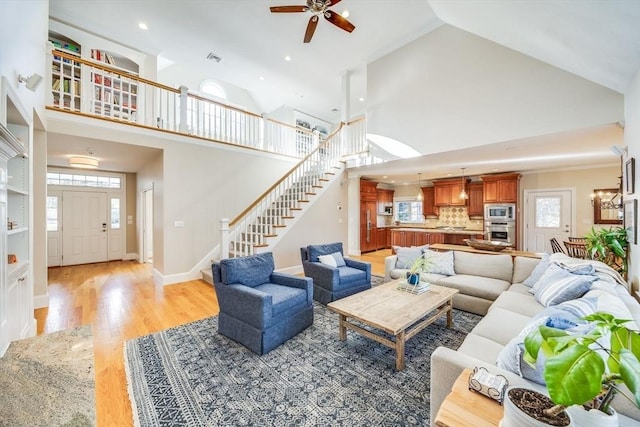 living room featuring light wood-type flooring, high vaulted ceiling, and ceiling fan