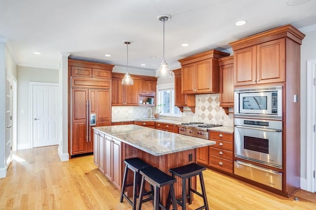 kitchen with sink, a kitchen breakfast bar, light stone counters, built in appliances, and a kitchen island