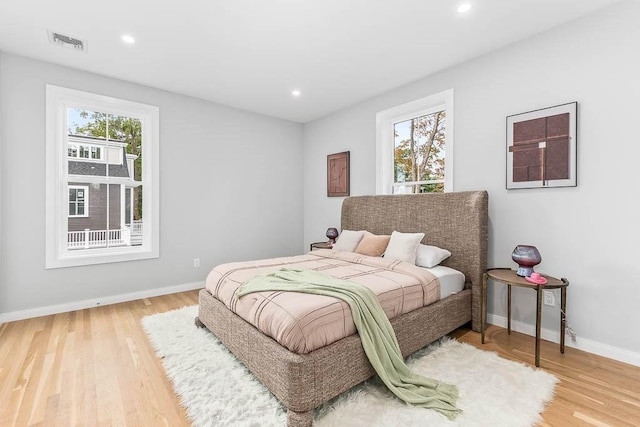 bedroom with multiple windows and hardwood / wood-style floors