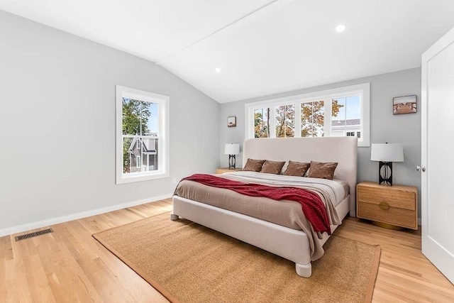 bedroom featuring multiple windows, hardwood / wood-style floors, and lofted ceiling