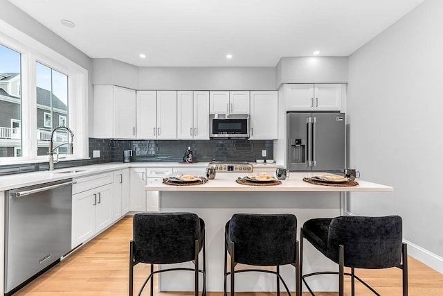 kitchen with sink, appliances with stainless steel finishes, a kitchen breakfast bar, a kitchen island, and white cabinets