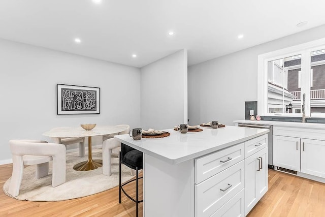 kitchen featuring white cabinetry, light wood-type flooring, a kitchen breakfast bar, and a kitchen island