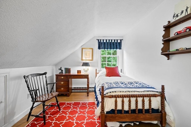 10 Granada Way, Andover, MA 01810 - bedroom featuring a baseboard heating unit, vaulted ceiling, a textured ceiling, and wood finished floors