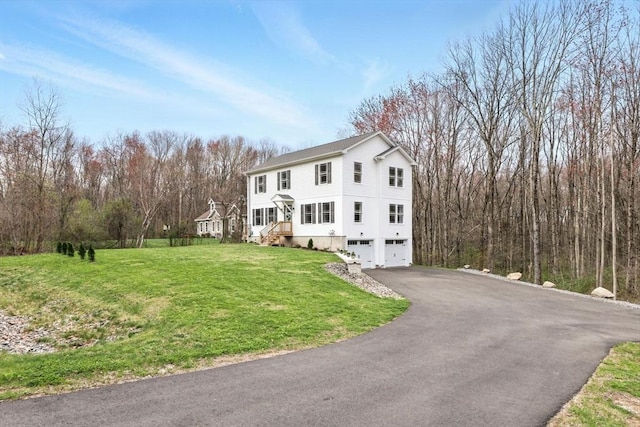 view of front of house featuring a garage, aphalt driveway, and a front yard