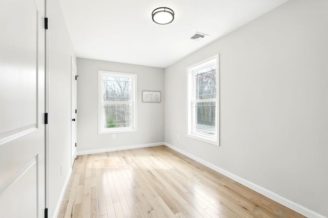 unfurnished room featuring baseboards, visible vents, and light wood finished floors