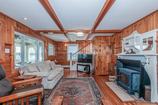 living room featuring wooden walls, a wood stove, beamed ceiling, hardwood / wood-style flooring, and coffered ceiling