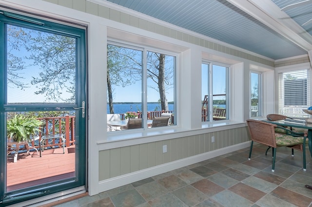 sunroom featuring a water view