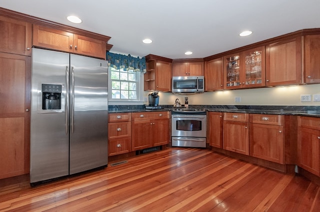 kitchen featuring appliances with stainless steel finishes, dark stone countertops, and hardwood / wood-style floors