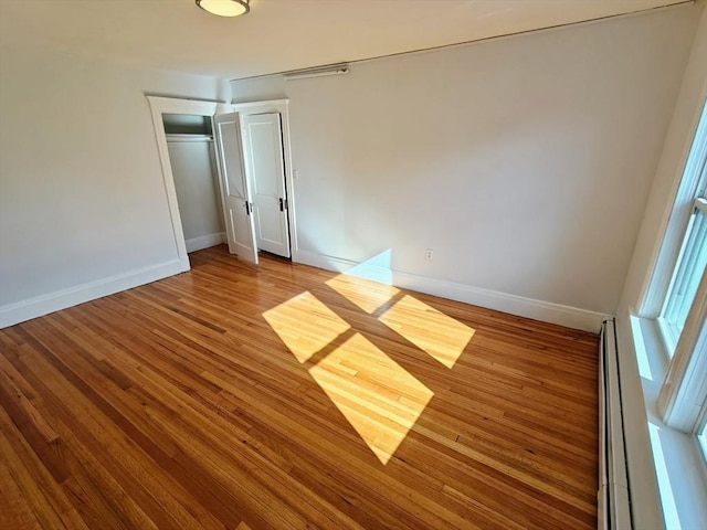 unfurnished room with wood-type flooring and baseboard heating