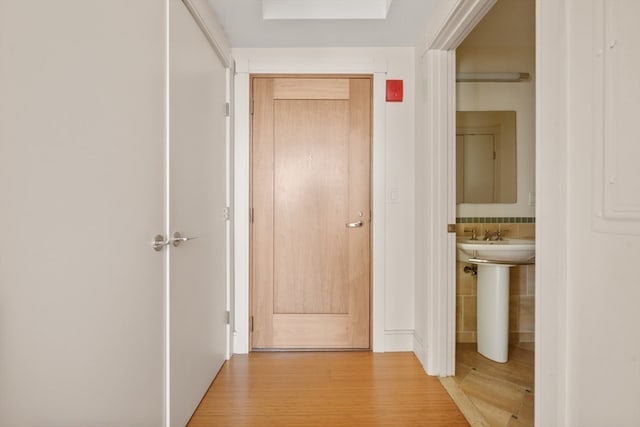 corridor featuring tile walls, light hardwood / wood-style floors, and sink