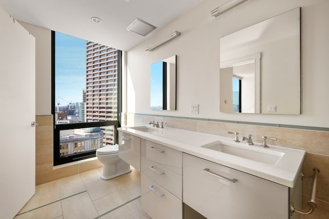 bathroom featuring vanity, toilet, tile walls, and a healthy amount of sunlight