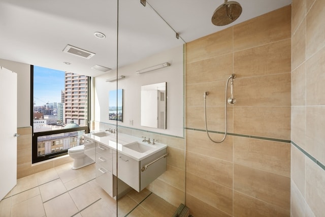 bathroom with tile patterned flooring, toilet, a tile shower, tile walls, and vanity