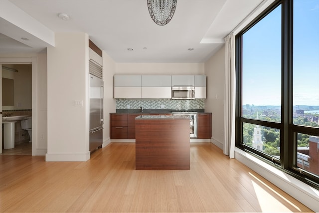 kitchen featuring a center island, stainless steel appliances, light hardwood / wood-style flooring, and decorative backsplash