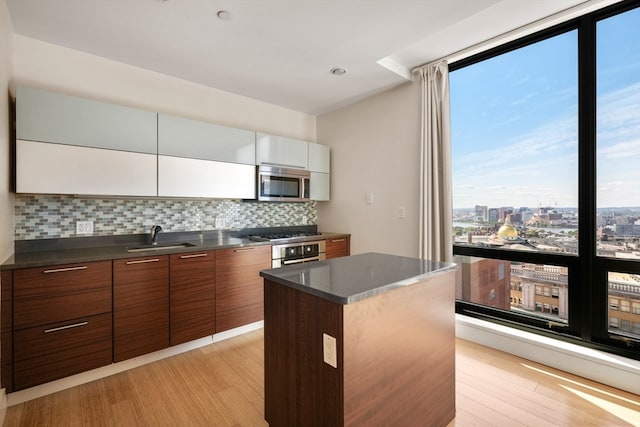 kitchen featuring appliances with stainless steel finishes, a center island, sink, and light hardwood / wood-style flooring