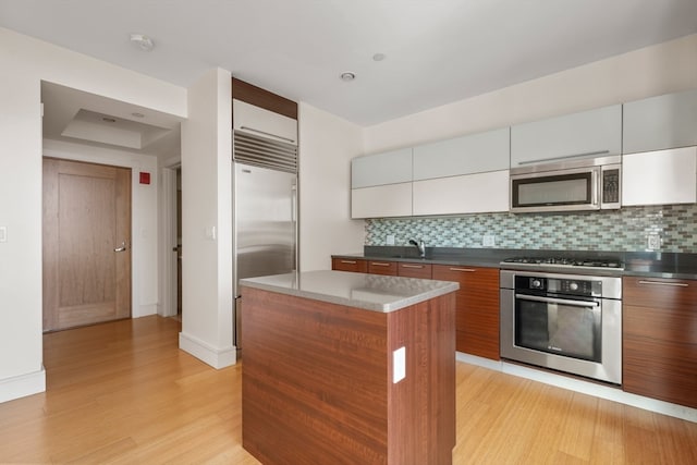 kitchen featuring tasteful backsplash, a center island, stainless steel appliances, sink, and light wood-type flooring