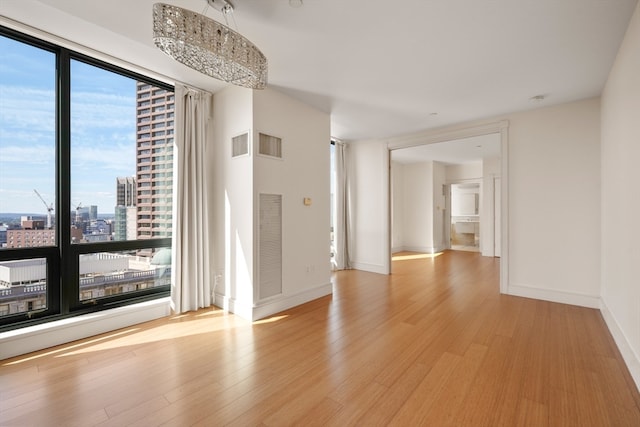 unfurnished room with light hardwood / wood-style flooring and a chandelier