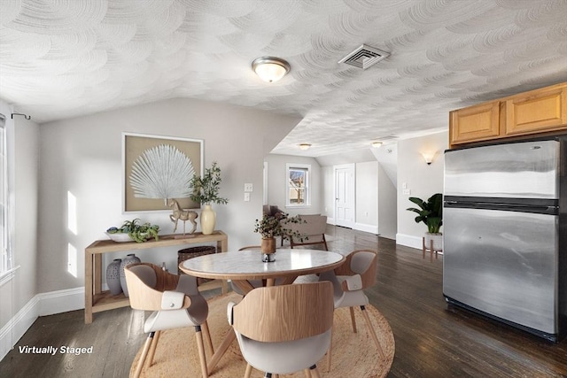 dining room with a textured ceiling, vaulted ceiling, and dark hardwood / wood-style floors