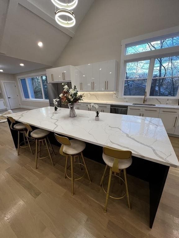 1 Harvard Ave, Burlington, MA 01803 - kitchen with freestanding refrigerator, high vaulted ceiling, a kitchen breakfast bar, white cabinets, and dishwasher