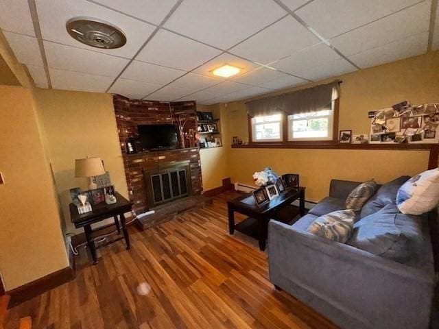 139 Westmoor Rd, Boston, MA 02132 - living room featuring wood finished floors, a paneled ceiling, a fireplace, and a baseboard radiator