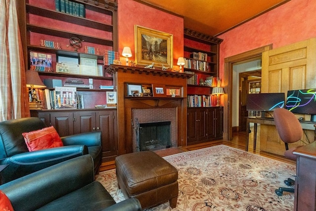 interior space featuring a fireplace with flush hearth, built in shelves, and wood finished floors