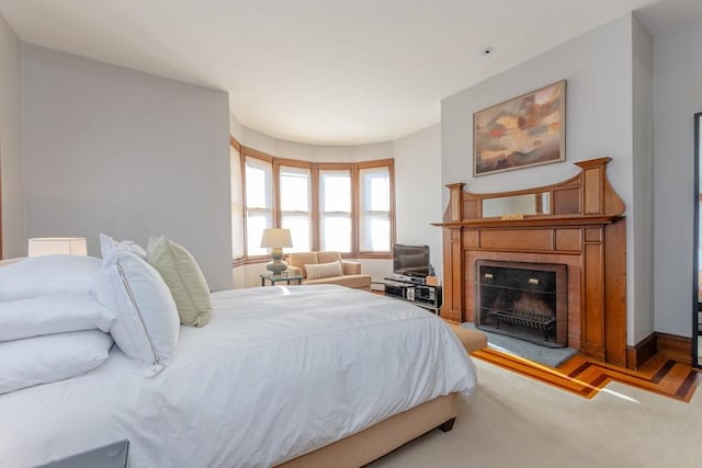 bedroom with light colored carpet and a tile fireplace