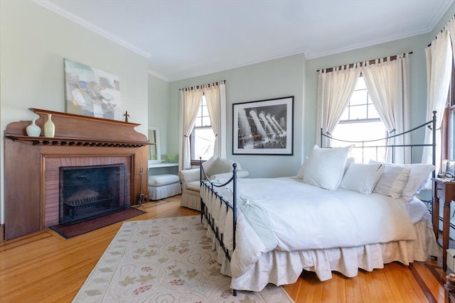 bedroom with a fireplace, wood finished floors, and crown molding