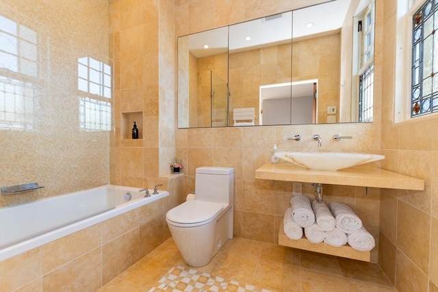 bathroom with a relaxing tiled tub, a sink, tile walls, and toilet