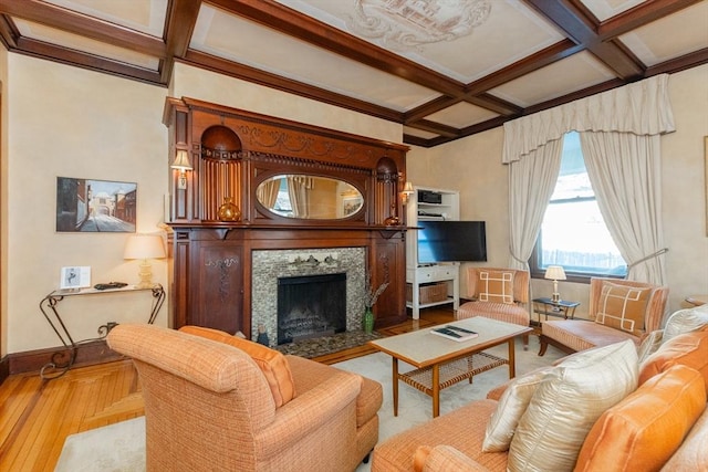 living area featuring beam ceiling, wood finished floors, a tile fireplace, coffered ceiling, and baseboards